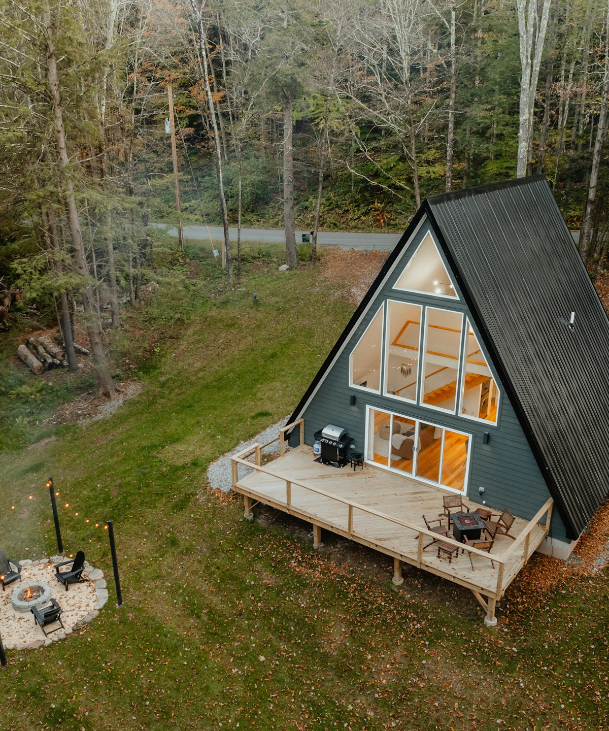 The A-frame cabin with its deck and fire pit at the edge of the meadow, seen from above